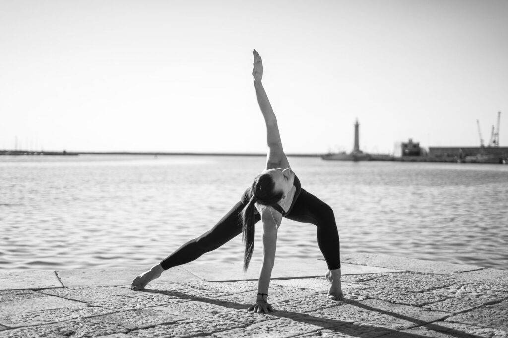 Posizione yoga sul molo di Molfetta, con il faro sullo sfondo